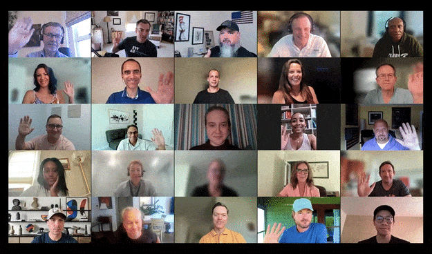 A virtual meeting with twenty-five people waving at their cameras, each in individual spaces with various background elements like books and decorations.